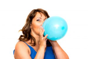 49744044 - beautiful middle-aged woman inflates a balloon. isolated on white.